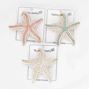 Detail showing three pearl starfish brooches in pink, blue and white on display card