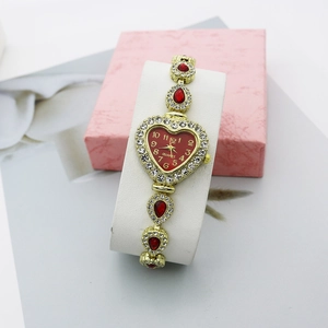 Vue détaillée d'une montre cœur en or avec cristaux rouges et cadran à quartz
