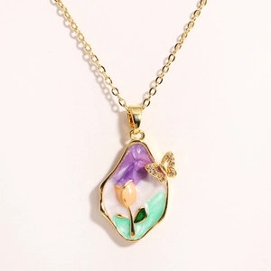 Detailed macro of gold tulip enamel pendant with natural freshwater pearl and crystal butterfly