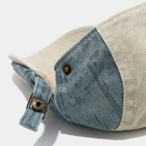 Detail of vintage bronze adjustable metal buckle on blue denim and beige canvas patchwork hat