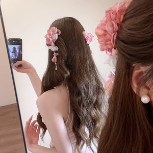 Détail d'une pince à cheveux en soie rose avec pétales blancs et glands en perles