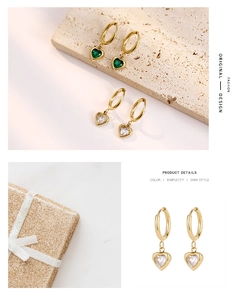 Détail de boucles d'oreilles cœur en or avec zircon émeraude et boîte cadeau