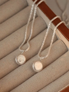Detail of two S925 sterling silver necklaces with baroque pearl pendants on a display tray