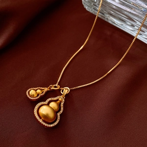 Detail of gold double gourd pendant with matte finish and pavé zircon on silk background