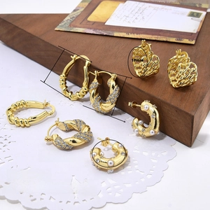 Detail of 18k gold plated U-shaped twisted earrings with zircon and pearls in macro view
