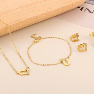 Dettaglio del set gioielli cuore dorato con collana bracciale e orecchini su fiori secchi