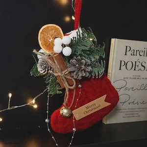 Handmade red knit Christmas stocking with pine cones, dried orange, and cinnamon decoration