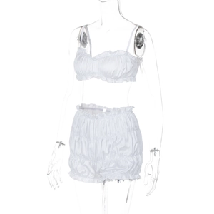 Detail of white two-piece set featuring ruffled bandeau top and pleated pumpkin shorts