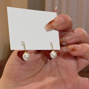 Macro view of French vintage red heart earrings with white pearls and gold accents