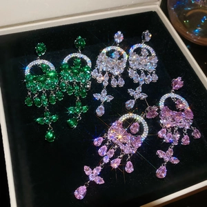 Close-up of three pairs of luxury zircon tassel earrings in green, white, and pink