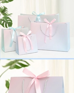 Detail of pink and blue gradient gift bags with silk ribbon handles and bows in various sizes