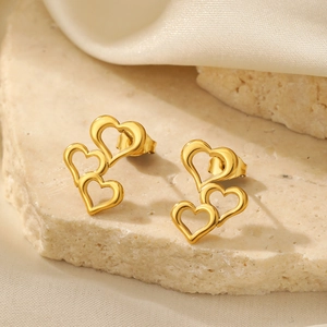 Detailed view of layered 14K gold-plated heart-shaped earrings on light stone