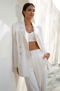 Detail of white women's suit featuring golden double-breasted buttons and high-waist pants