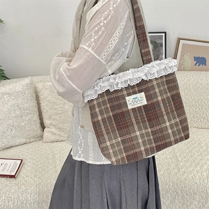 Close-up of brown plaid tote bag featuring white lace trim and happy patch detail