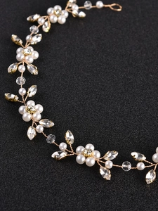 Detail view of bridal headpiece with white pearls and gold wire floral leaf patterns