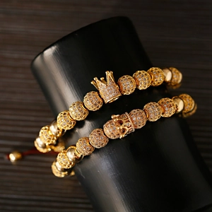 Detail of two gold crown bracelets with micro-pave cubic zirconia on a black display