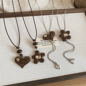 Detail of leopard print heart and flower pendants with crystals on elegant necklaces