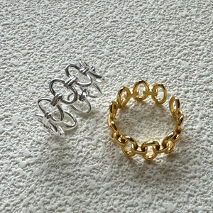 Pair of gold and silver chain link S925 sterling silver rings on textured background