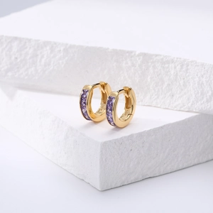 Détail de boucles d'oreilles créoles dorées s925 avec zircon violet sur pierre