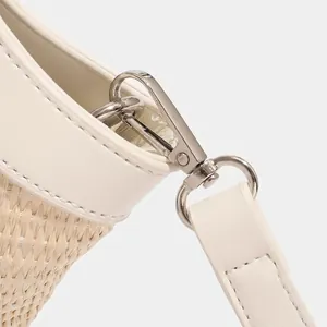 Detailed macro view of woven handbag showing beige leather stitching and silver hardware hooks