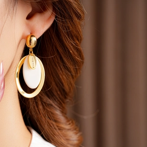 Detail of gold oval drop earrings with white resin pendant and Hand Made engraving