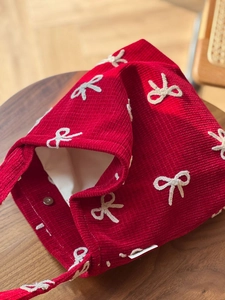 Macro shot of red corduroy tote with white bow embroidery and metallic snap button