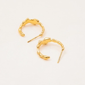 Macro detail of 18K gold-plated C-shape earrings with hammered lava texture
