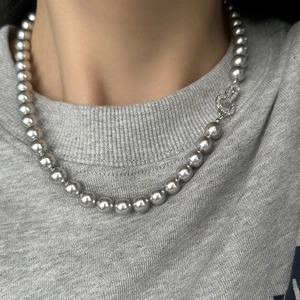 Elegant grey pearl necklace with a silver diamond clasp worn by a model in soft light