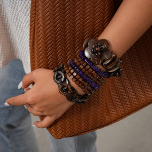Dettaglio di un bracciale multistrato boho con perle di legno e ciondoli viola