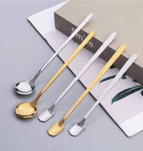 Detail of square and round head long handle stainless steel spoons in gold and silver finish