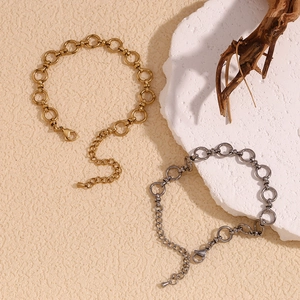 Close-up of gold and silver stainless steel chain bracelets on a minimalist background