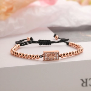 Macro shot of rose gold bead bracelet with zircon crown pendant on woven cord