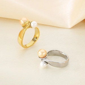 Polished stainless steel double pearl rings in gold and silver finishes on beige fabric