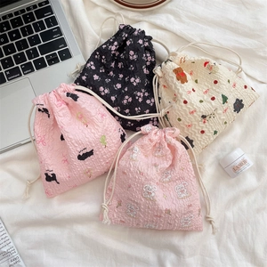 Flat lay of small drawstring storage bags with cute cartoon prints in seersucker fabric