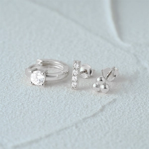 Detail of three-piece silver earring set with CZ diamonds on textured grey stone