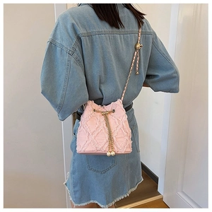 Detail of pink denim bucket bag with quilted texture, gold chain and pearl charms