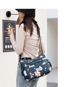 Deep blue crossbody bag with red floral print and multiple zip compartments on model