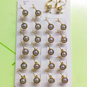 Macro detail of 12 pairs of gold plated stainless steel grey pearl hoop earrings