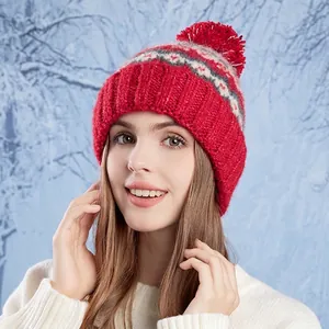 Winter knit beanie for women in vibrant red with grey patterns and a large fluffy pom-pom