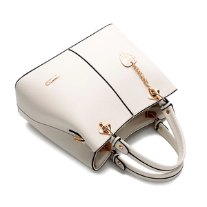 Detailed close-up of white PU leather handbag with rose gold heart pendant and metal logo