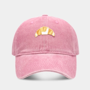 Detail showing high-quality croissant embroidery on a pink washed cotton baseball cap