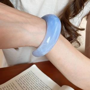Detail of wide light blue resin bangle with natural white cloud texture on a model