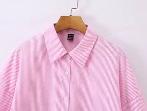 Dettaglio ravvicinato del colletto di camicia a righe rosa e bianche con bottoni