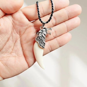 Detailed view of wolf head pendant with resin fang on black braided necklace cord