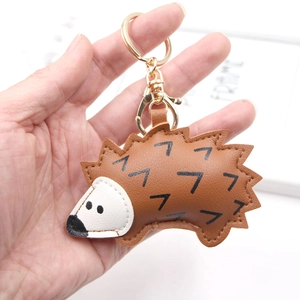 Close-up of cute brown PU leather hedgehog keychain with golden metal ring and clasp