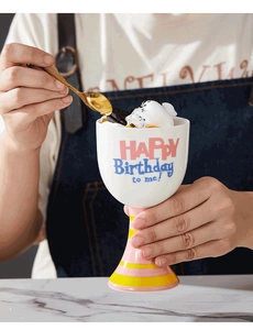 Macro shot of a white ceramic dessert cup with birthday lettering and striped base