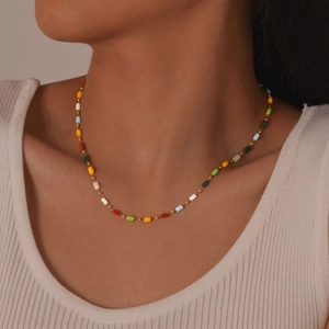 Detail of colorful square beads and gold round beads on a layered stainless steel necklace