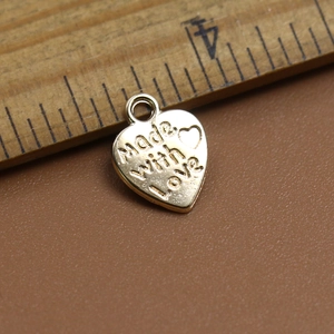 Detalle de un colgante de corazón grabado con Made with Love en una superficie