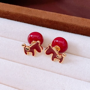 Close-up of red enamel puppy stud earrings in a luxury cream velvet jewelry box