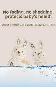 Close-up of knit bunny baby teether with natural wooden ring in a water splash scene
